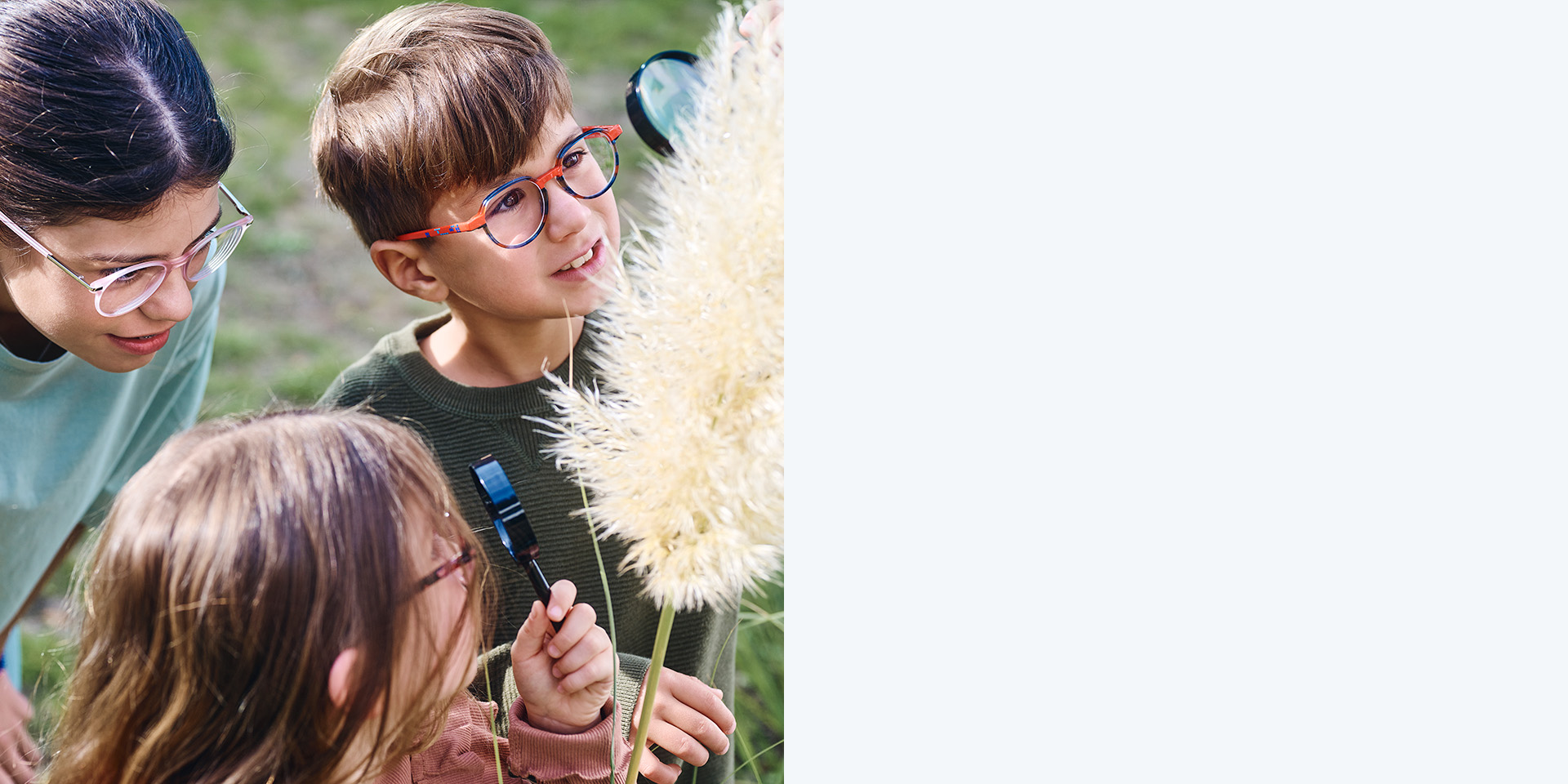 2 dziewczynki i chłopiec noszący soczewki ZEISS MyoCare. Patrzą na roślinę, dwoje z trojga dzieci patrzy na roślinę przez okulary powiększające.