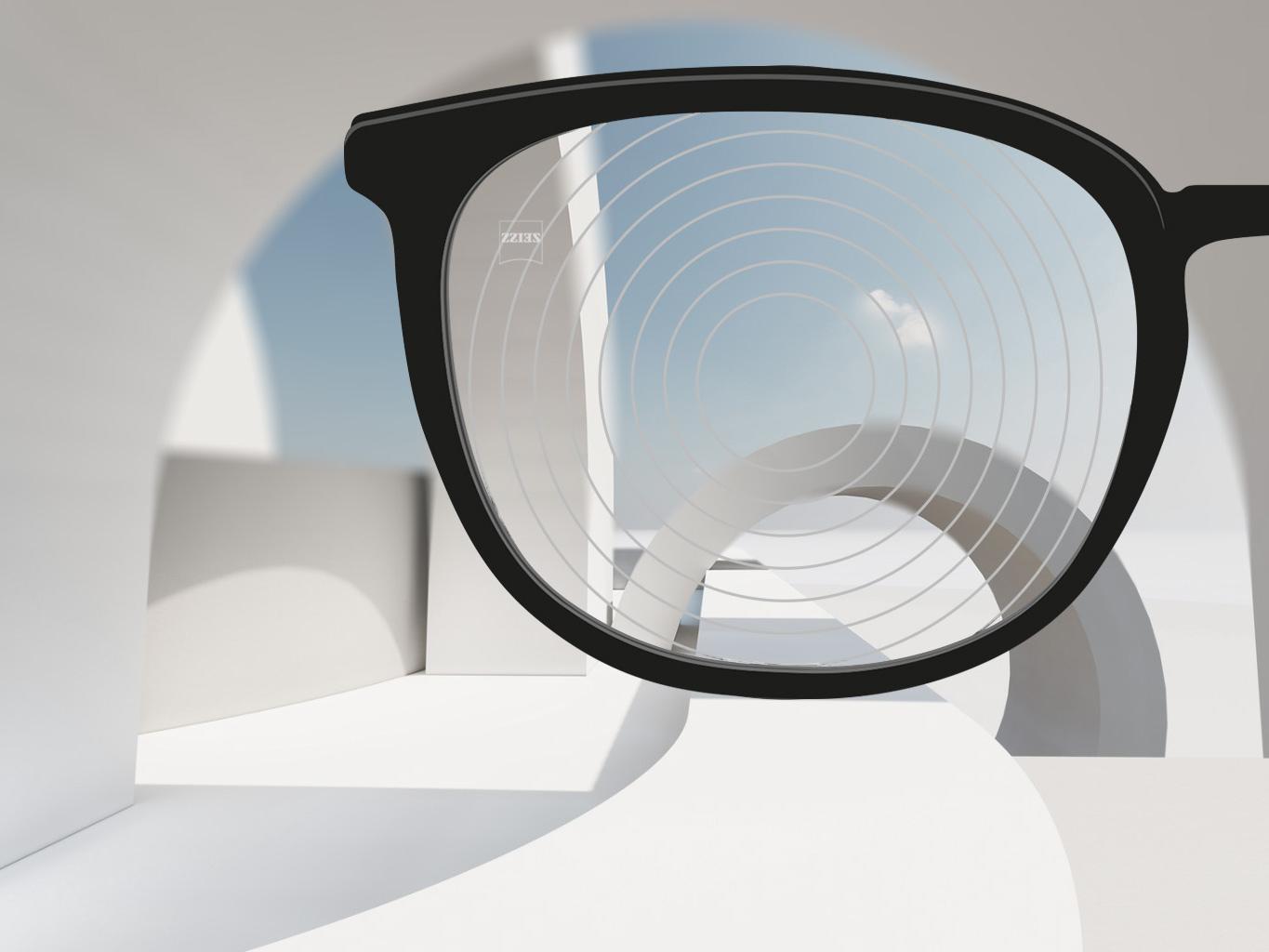 Przybliżony obraz soczewek ZEISS zwalczających krótkowzroczność z czarnymi oprawkami okularowymi i okręgami koncentrycznymi na powierzchni soczewki. 