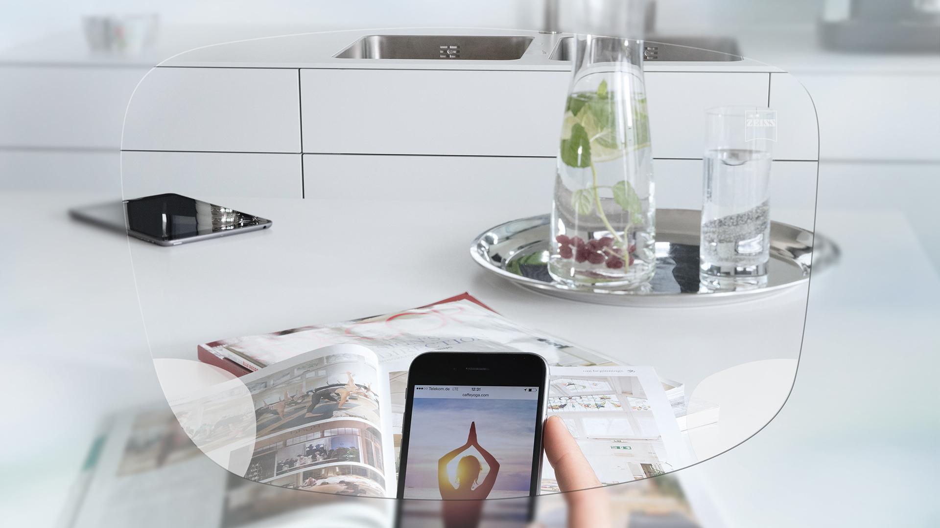 Widok na ekran smartfona i stół kuchenny przez jednoogniskowe soczewki ZEISS EnergizeMe 