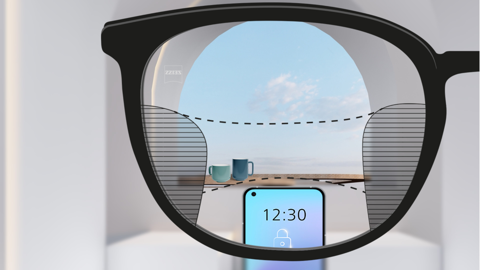 Punkt widzenia z soczewkami progresywnymi ZEISS SmartLife ze smartfonem i kubkami w tle, obraz widziany przez soczewkę jest w pełni wyraźny z wąskimi rozmytymi obszarami po lewej i prawej stronie.