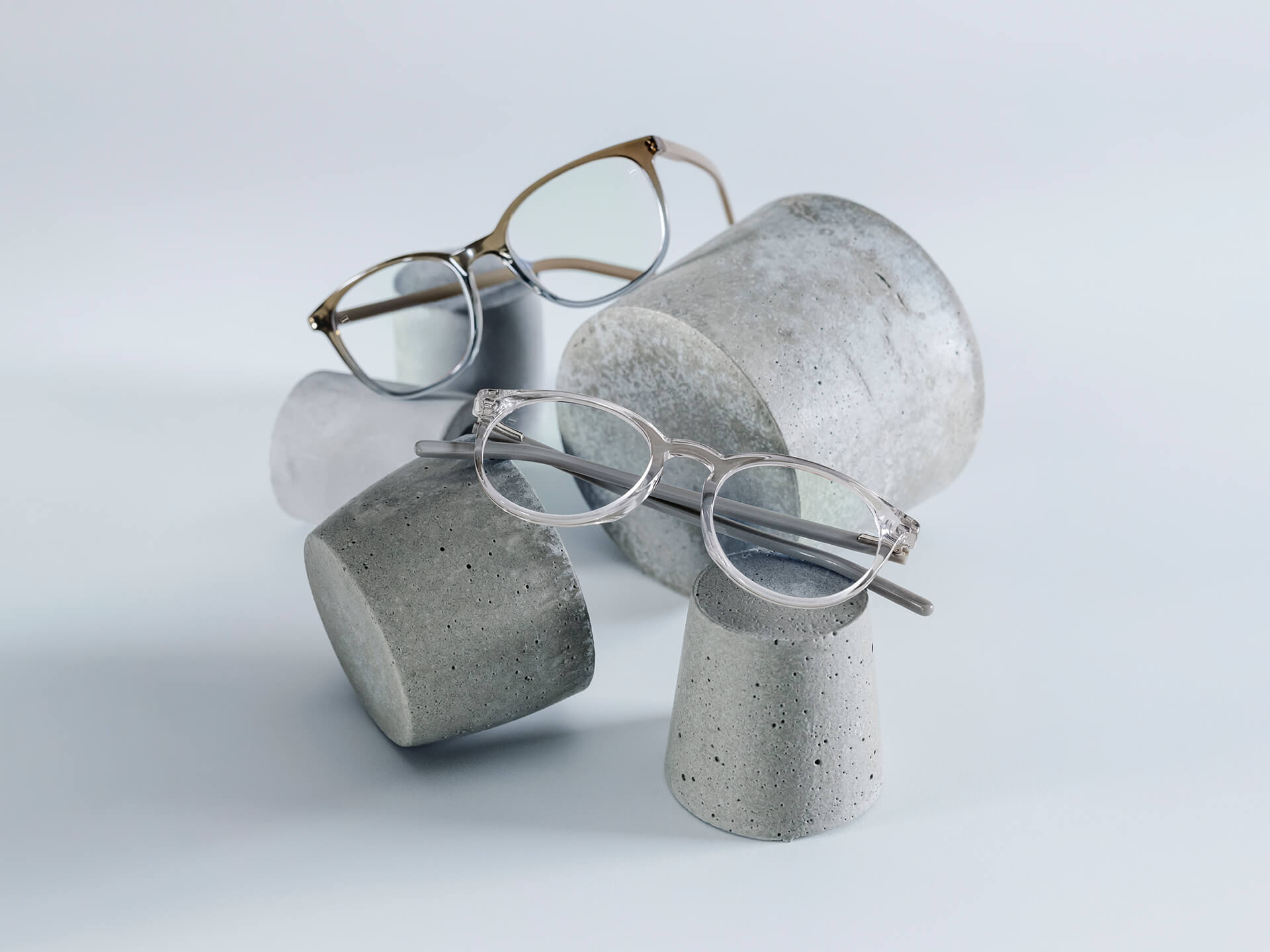 Okulary z soczewkami ZEISS, wyposażone w powłokę DuraVision® Chrome leżą na kamiennych postumentach różnych rozmiarów.