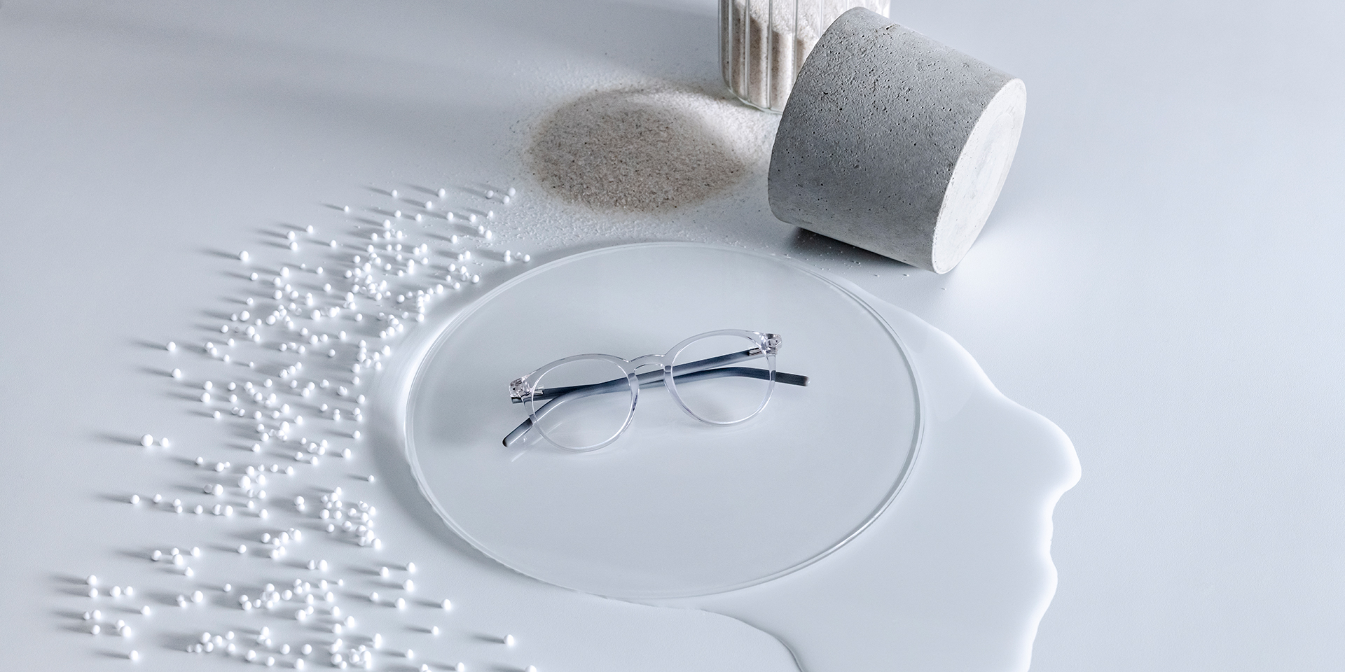 Soczewki ZEISS z powłoką DuraVision® umieszczone na szklanym postumencie otoczonym wodą, piaskiem, kryształkami i kamieniami.
