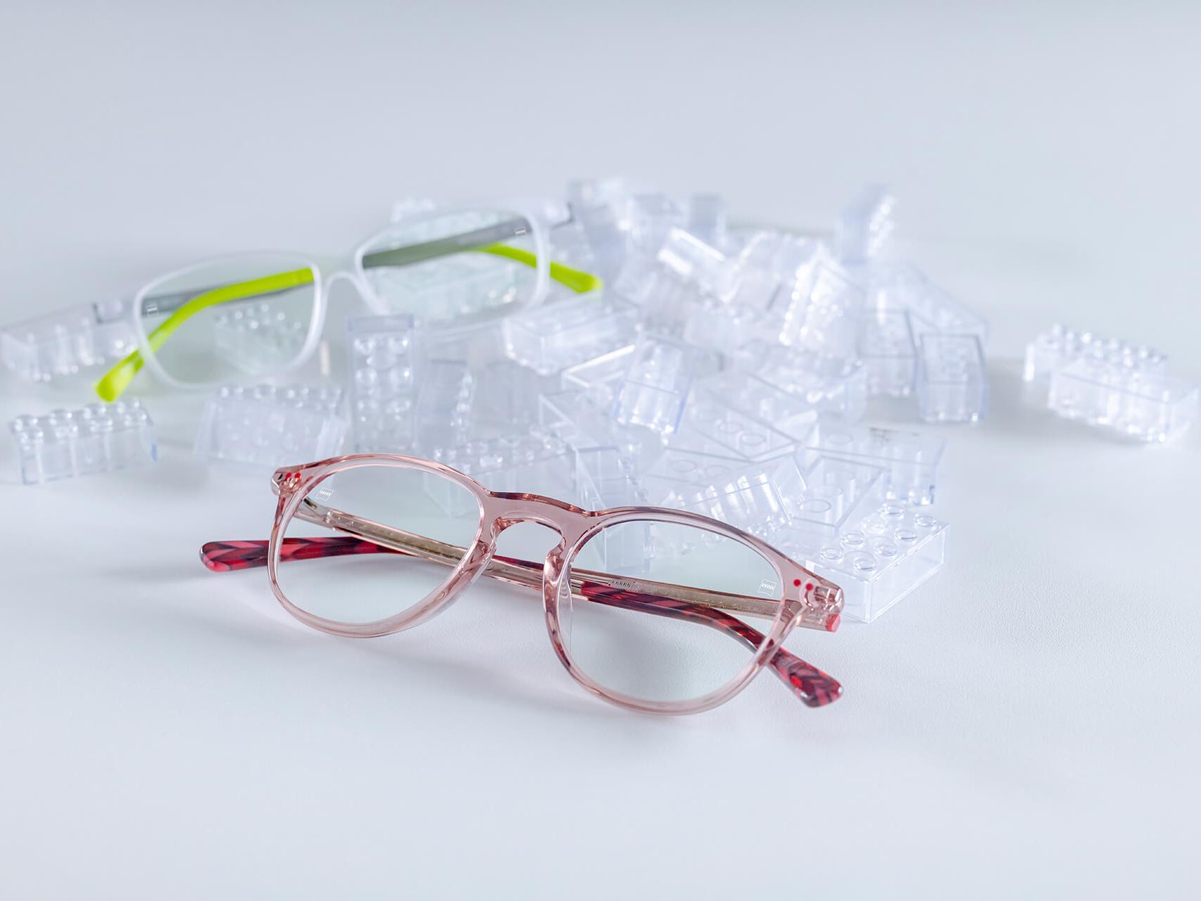 Dwie pary dziecięcych okularów z soczewkami ZEISS i powłoką DuraVision® Kids. Okulary zostały umieszczone między przezroczystymi klockami dla dzieci.