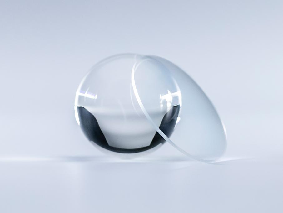 Soczewka z powłoką ZEISS Platinum jest krystalicznie czysta i nie odbija światła w porównaniu do znajdującej się obok szklanej kuli.