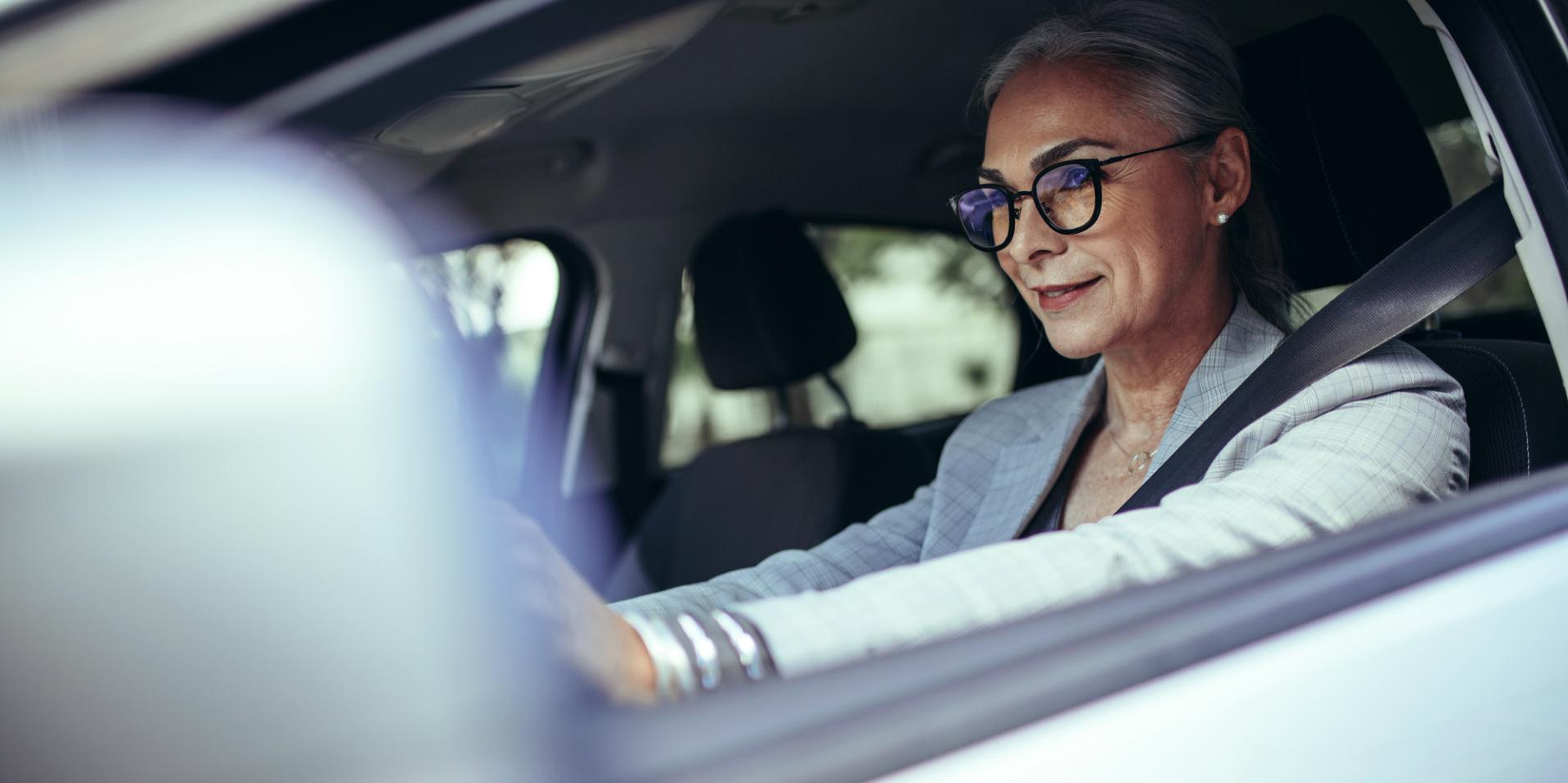Starsza kobieta jedzie samochodem, nosząc okulary z soczewkami ZEISS DriveSafe.