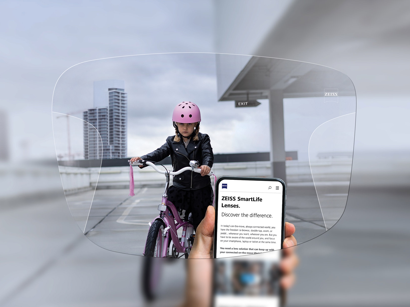 Osoba spoglądająca na telefon przez okulary z soczewkami progresywnymi ZEISS SmartLife. W tle widać rowerzystkę w różowym kasku. 