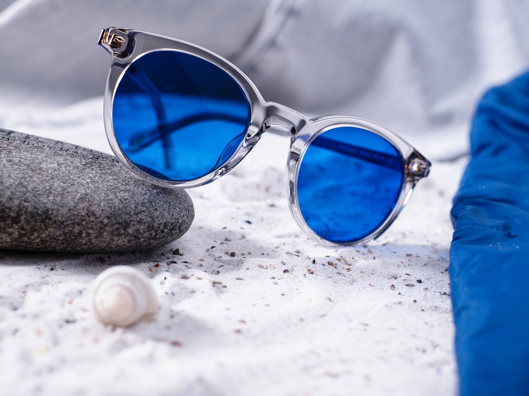 Zdjęcie pary okularów przeciwsłonecznych z niebieskim barwieniem, częściowo leżących na kamieniu